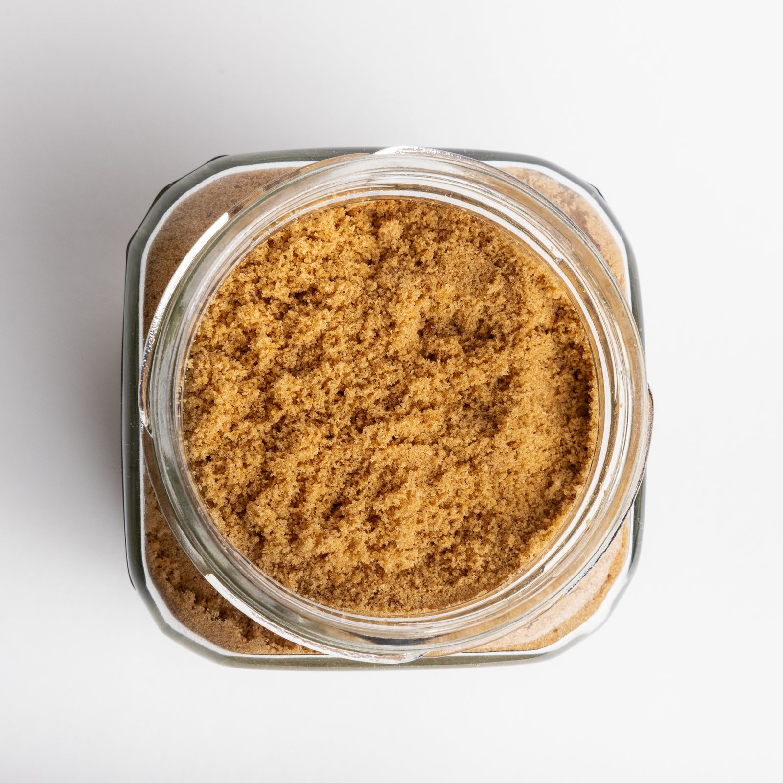 Glass jar filled with brown sugar on a white background