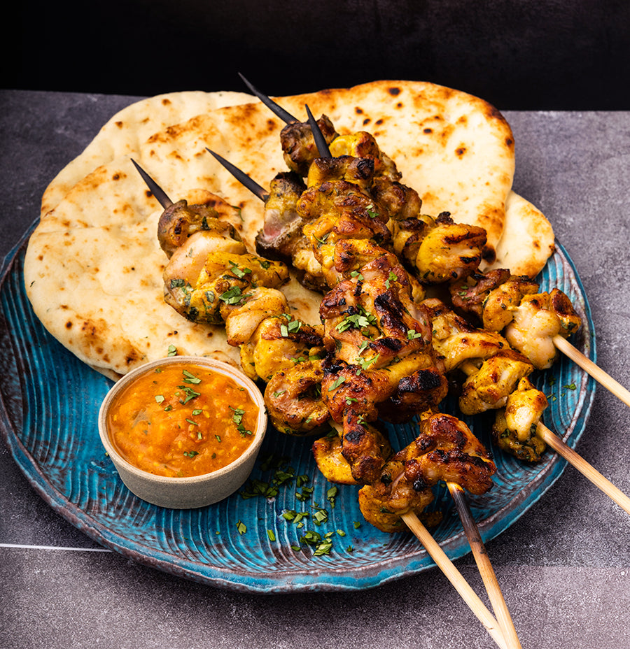 Blue plate with flatbread, Kathmandu Curry chicken kebab, and achar sauce.