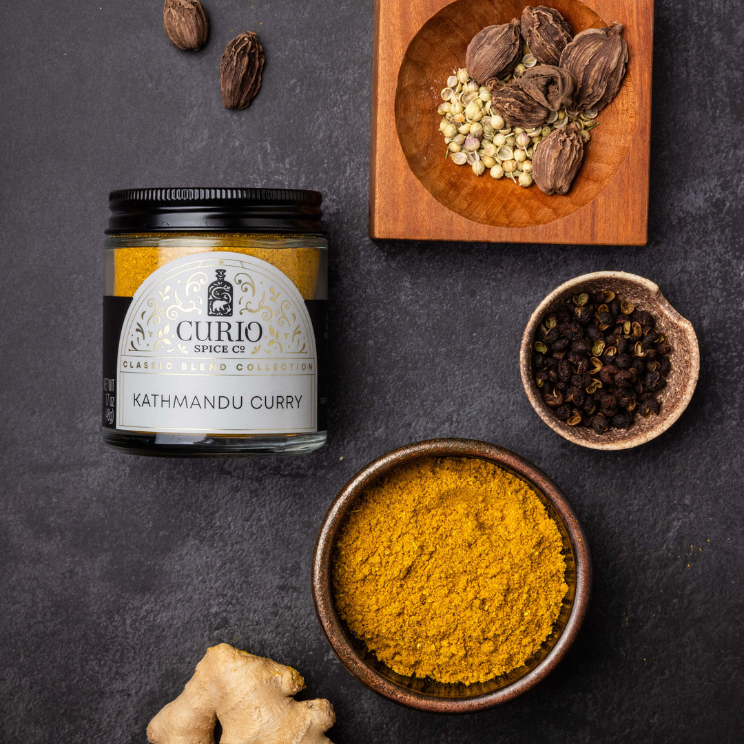 Curio Spice Co. Kathmandu Curry spice jar with ingredients on a dark surface