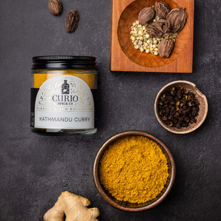 Curio Spice Co. Kathmandu Curry spice jar with ingredients on a dark surface