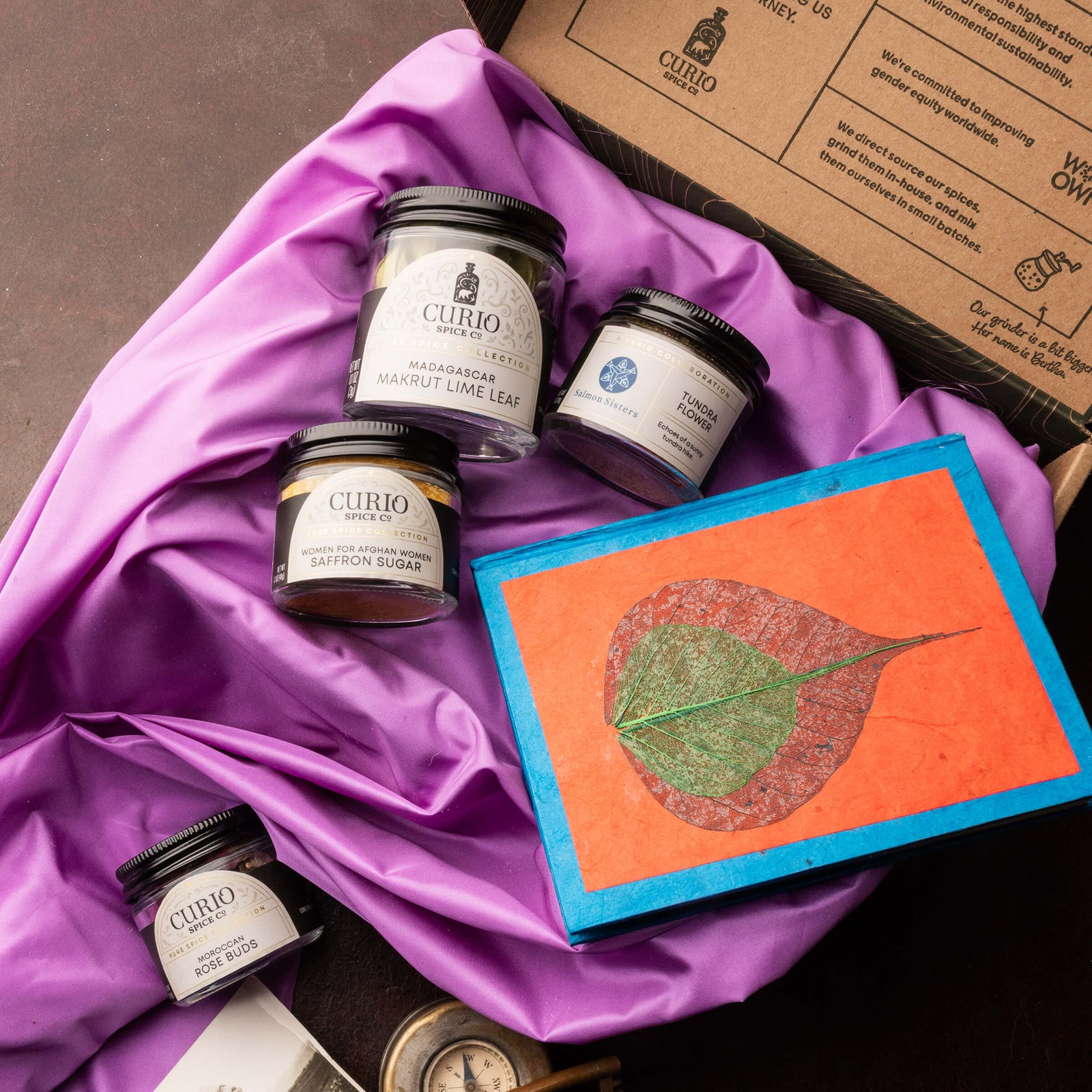 Curio products on a purple fabric with a decorative notebook