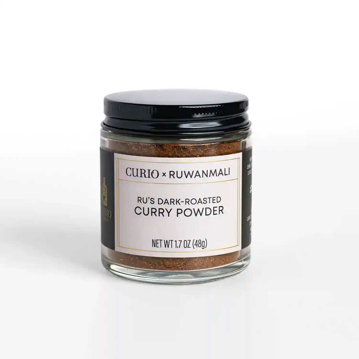 A glass jar of Ru's Dark-roasted Curry Powder, a collaboration blend with Curio Spice and Ruwan Samarakoon