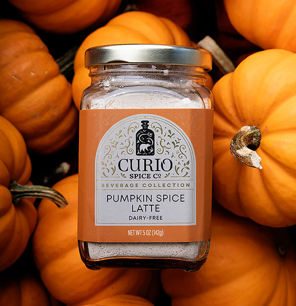 Jar of Curio Spice Co. Pumpkin Spice Latte mix surrounded by pumpkins