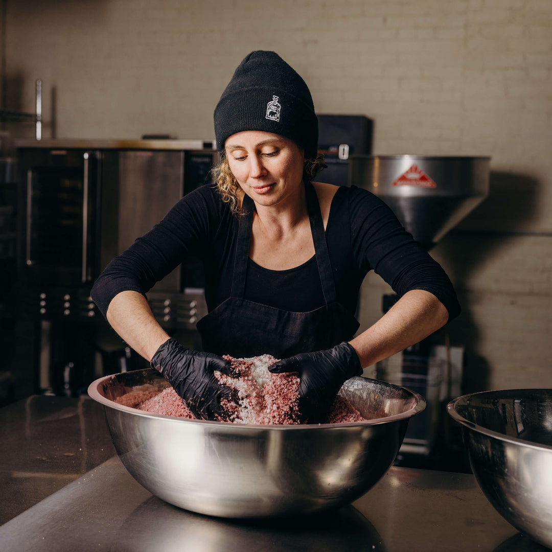 Claire Cheney mixing a large bowl of spices in the production facility