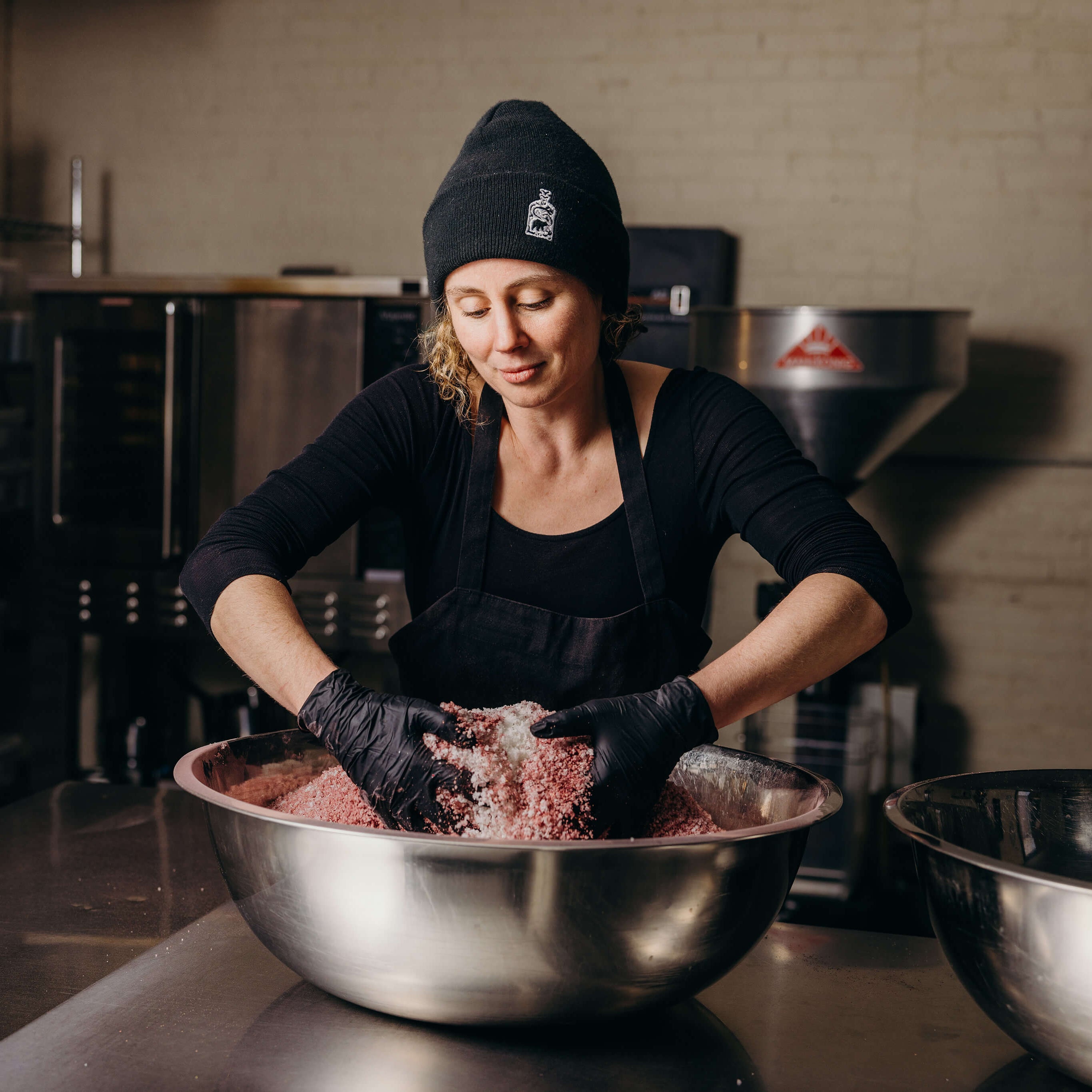 Claire Cheney mixing a large bowl of spices in the production facility