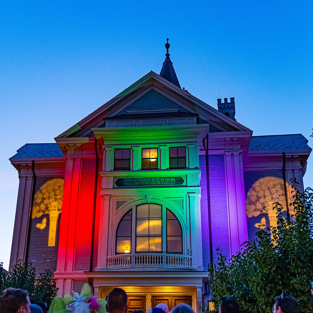 Historic building illuminated with red, green, and purple lights against a blue sky.