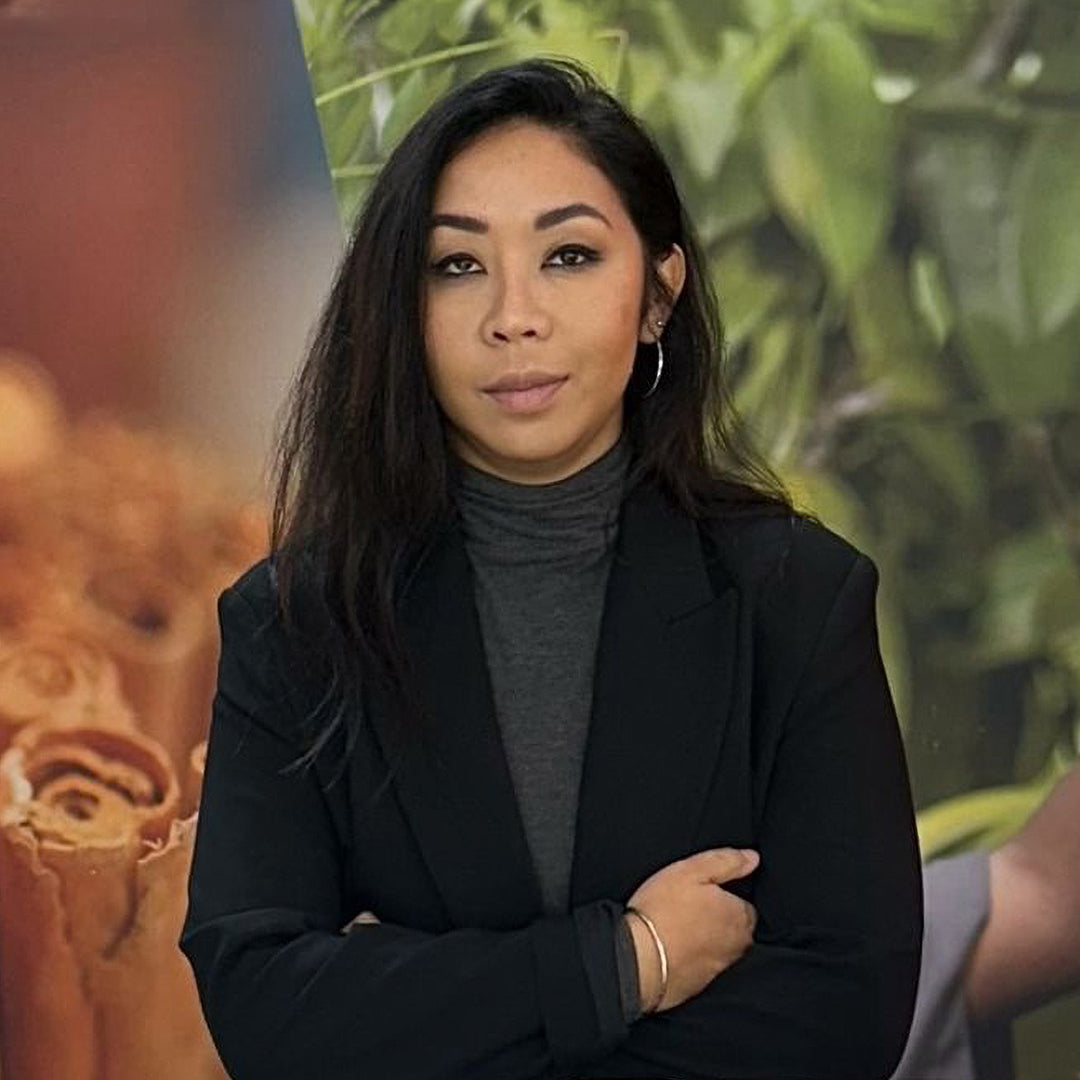 Woman in a black blazer standing in front of a blurred background
